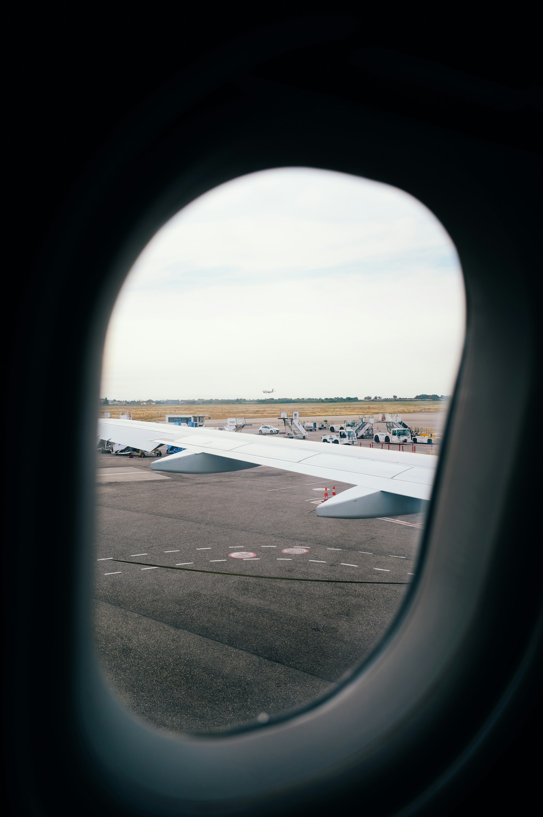 Flugzeugflügel am Vorfeld, gesehen durch ein Flughafenfenster